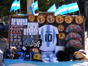 Souvenirs (e.g., keychains, magnets, hats, flags, fans, etc) are displayed in a street-vendor cart/stand at Plaza de Mayo in Buenos Aires, Argentina.