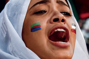 From the cover of Ghaḍab wa-Kandākāt : riwāyah (Bayrūt: Hāshīt Anṭwān, 2020) by the Sudanese novelist Amir Tag Elsir, a woman in a white headscarf with color stripes on her cheeks.