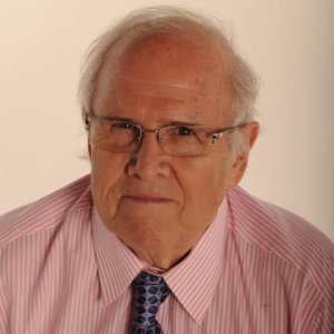 head shot for Thomas DeFrank with Mr. DeFrank wearing glasses, a pink collared shirt and dark tie