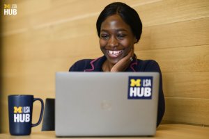 A Black student sits at the Hub table on their computer.