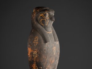 The head and shoulders of a corn mummy coffin depicting the falcon face of the Egyptian god Horus.