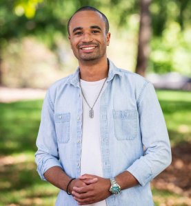 Photo of Caleb Jeanniton with a blue shirt and natural background