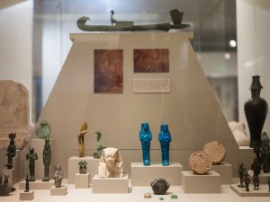 View of a Kelsey Museum vitrine containing an array of small artifacts from ancient Egypt, including ushabtis and bronze figurines.