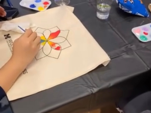 Student painting a canvas bag