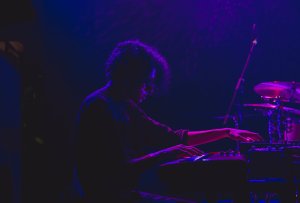 Man at keyboard playing in dark/purple lighting