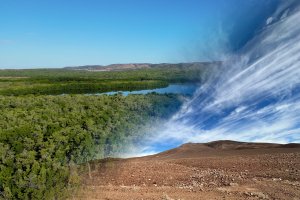 Two landscapes merged together, one of a forested area with a river and the other of a barren rocky plain with mountains in the background.