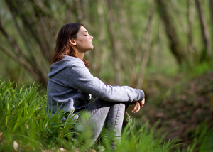 Person sitting outside in nature with eyes closed