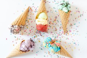 five ice cream cones on a white backdrop with sprinkles
