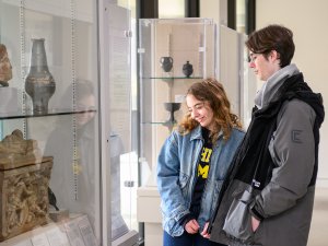 A man and a woman look at Greek and Etruscan objects on display at the Kelsey Museum.