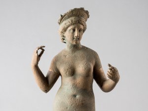 Nude statue of the goddess Aphrodite, standing with her arms upraised and wearing a diadem.