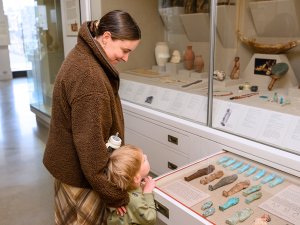 A woman and young boy open a drawer in the Kelsey Museum’s Egyptian galleries containing a small assemblage of blue and brown ushabti figurines.