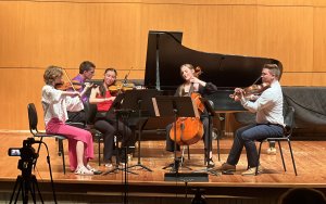 A string quartet and pianist perform on stage.