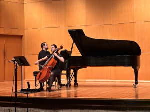 A solo cellist and collaborative pianist perform on stage.