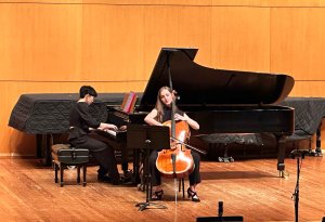 A solo cellist and collaborative pianist perform on stage.