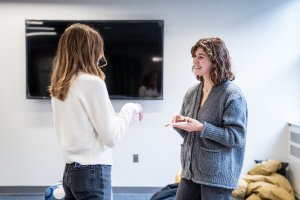 Two people talk while holding a donut on a plate