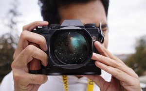 Image of a man holding a camera with a galaxy in the lens