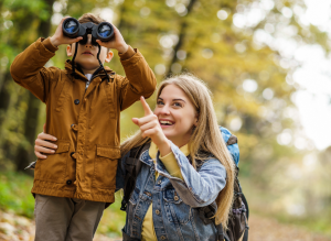A mother pointing and son using binoculars to look at nature