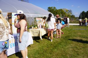 Organizations tabling on a sunny day in front of a hoop house