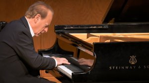Arthur Greene performs piano on stage.