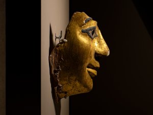 Profile of a fragment of a mummy mask in the Kelsey Museum, painted with gold and black.