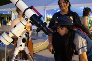A student looks through a telescope at Summerfest