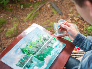 a person painting a watercolor painting of a forest