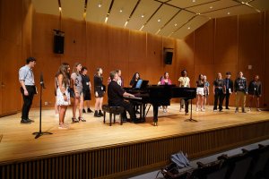 MPulse student vocalists perform with a pianist on stage.
