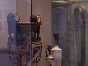 View into a Kelsey Museum glass case holding three pieces of Greek pottery, including a prominently displayed red-figure krater with the face of Medusa on each of its scrolled volutes.