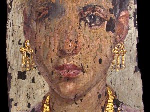 A chipped, painted mummy portrait of a woman wearing gold jewelry.