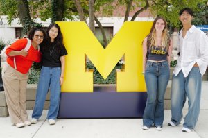 Students stand by a giant block M.