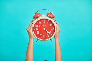 A person holding an analog clock
