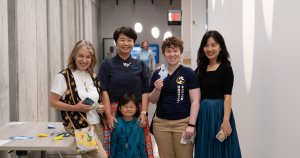 Four people and one child smile for the camera at Full Moon Festival. One person is holding an origami moon.