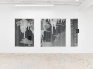 Three large, translucent hanging panels displayed in a white gallery space, featuring monochrome figures and dark rectangular accents.
