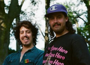 Adam and Zack Khalil stand, smiling, in a forest