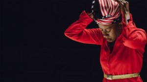 Holly Bass, a Black woman wearing an American flag head wrap and a red jacket.