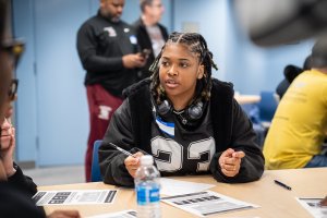 Student holds pens in hand while talking to another person off camera