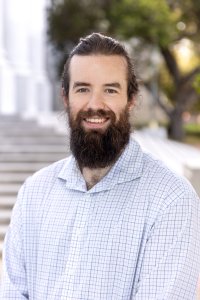 A man with a beard in plaid shirt smiles for the camera