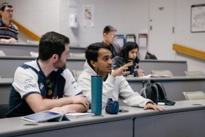 Two people talk while in a classroom