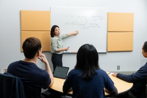 Professor points at a whiteboard