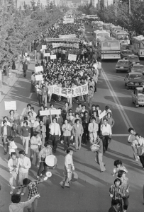 Captured by journalist Na Kyung-taek in May 1980, this image shows Chonnam National University students marching in Gwangju, South Korea, shortly before the May 18 Democratization Movement. Demonstrators carry banners demanding "Lift Martial Law Immediately" (계엄 즉각 해제), while students in front play traditional Korean drums (Pungmul) to rally the crowd against military rule.