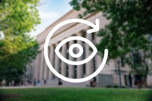 icon of an eye encircled with an arrow against a blurred image of Angell Hall