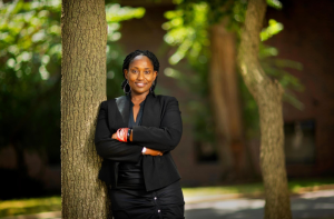 Marcia Chatelain in a black suit leaning against a tree
