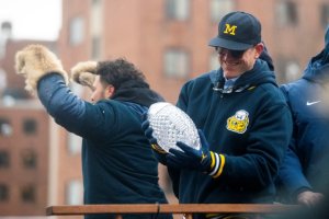 former U-M football coach Jim Harbaugh holding the AFCA trophy during the championship parade in Jan 2024.