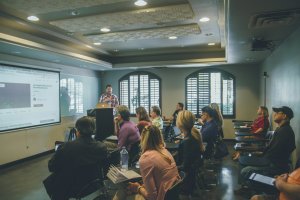 Lecture with individuals in a room facing a whiteboard