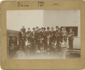 "U of M Band 1897" written by hand with a photo of 23 band members in two rows, holding instruments and wearing suits and top hats.