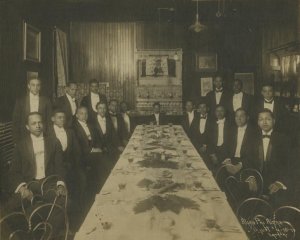 A group of Alpha Phi Alpha members gathered around a banquet table in 1910.