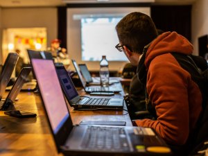 Stock image of students in a class looking at a presentation screen with laptop computers open