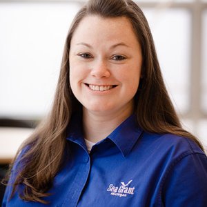 Dr Lauren Stigers with brown hair, wearing a blue collared SeaGrant shirt smiling at the camera