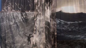 An abstract image of textured greys and browns, with the textures fading into photos of ocean waves. the silhouette of a black man jumping into the water is visible.