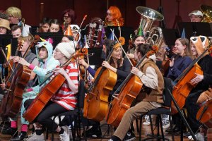 A close-up of orchestral musicians wearing various costumes for Halloween